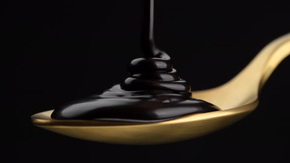 Chocolate. Pouring liquid dark chocolate in golden spoon. Confectionery concept. 4K UHD video