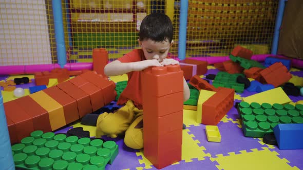 A Little Boy Assembles a Tower From a Large Construction Set