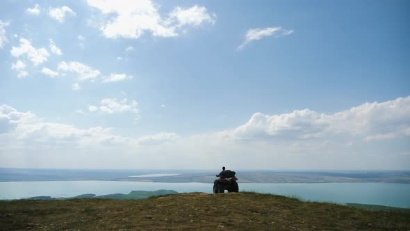 Man in a Black Cap and Red T-shirt on a Colored ATV Rides