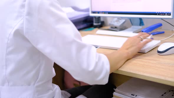 Woman Doctor Surgeon in White Uniform Types on the Computer Keyboard the Diagnosis and Examination