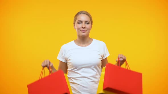 Smiling Pretty Lady Showing Shopping Bags on Orange Background, Holiday Sale