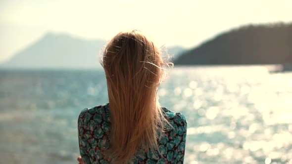 Woman Tourist Stands On Shore Enjoying Marine Views. Rocky Seacoast Beach. Girl Looking At Ocean.