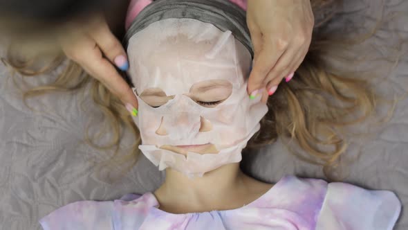 Teen Girls Mother Applying Moisturizing Face Mask on Daughter. Child with Cosmetic Facial Skin Mask