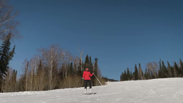 A Cheerful Woman Skis Down A Snowy Track At A Ski Resort And Dances Smiling