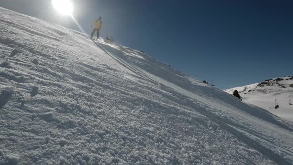 Skier going downhill while sprays snow in slow motion carving down the slope on a sunny day