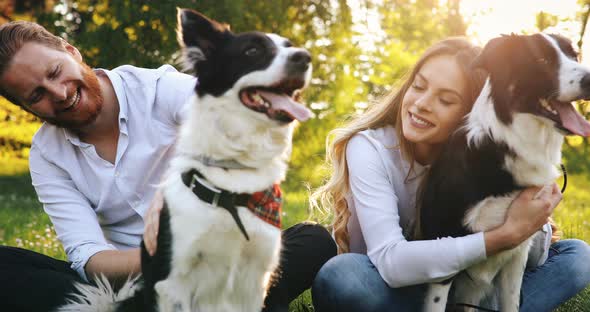 Beautiful Couple Cuddling and Walking Dogs Outdoors