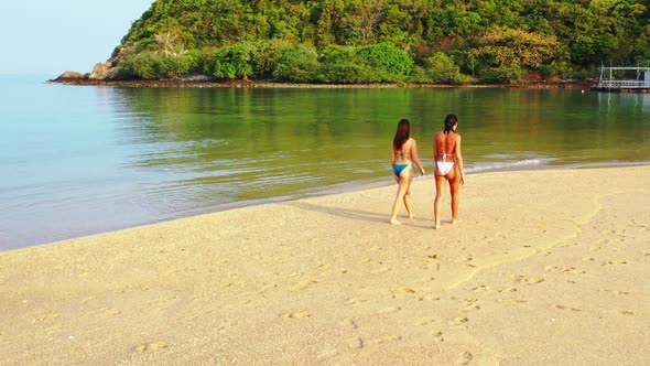 Girls happy together on perfect seashore beach adventure by blue ocean and white sandy background of