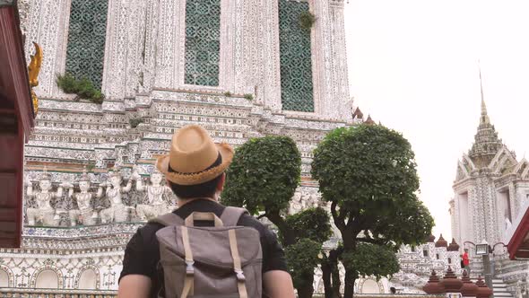 Young Asian Traveling Backpacker Looking Around in Wat Arun Temple Outdoor in Bangkok Thailand