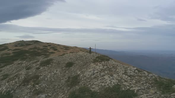 Male Tourist Raising Arms Carefree at the Top of the Mountain Watching the Panoramic View