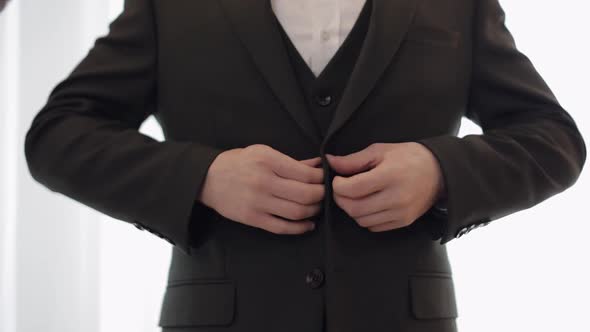 Groom Buttoning Jacket Man in Suit Fastens Buttons on His Jacket Preparing to Go Out