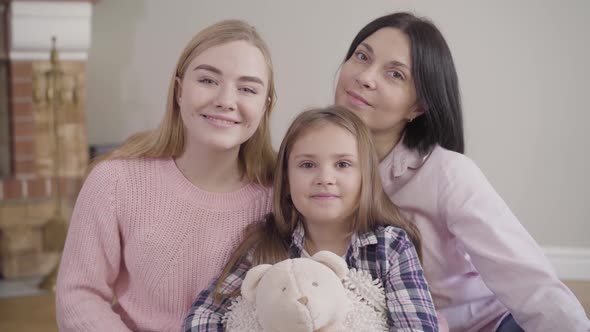 Portrait of Adult Caucasian Woman, Teenage Girl and Little Cute Child Looking at Camera and Smiling