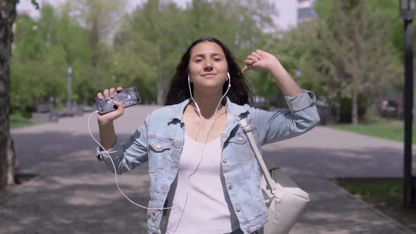 Funny Girl Walking Down the Street and Dancing Listening To Music on Headphones