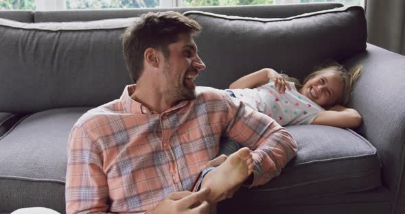 Father and daughter playing together on sofa at home 4k