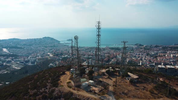 Communication towers are located on a mountain near the sea city.
