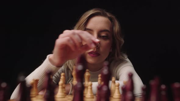 Beautiful Girl Playing Chess Board Game And Moving Pawn Piece With Black Background. - close up, POV