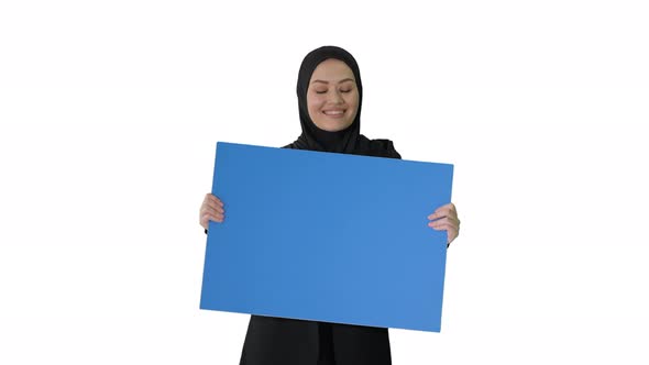 Smiling Arab Woman in Hijab Holding Blank Blue Poster and Looking at It on White Background.