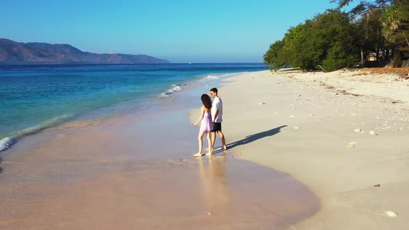 Two lovers in love on exotic seashore beach lifestyle by blue green lagoon with white sandy backgrou