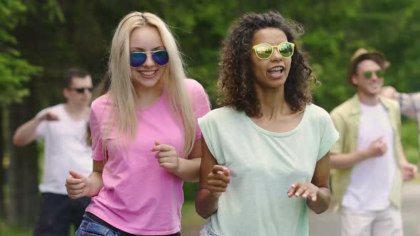 Two Female Friends Dancing and Talking at Party in Park, Guys Enjoying Summer