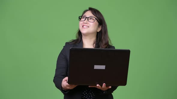 Mature Beautiful Asian Businesswoman Using Laptop Against Green Background