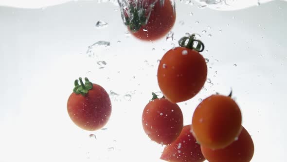 Closeup of Fresh and Health Cherry Tomatoes Falling Into Clear Water with Big Splash on Black