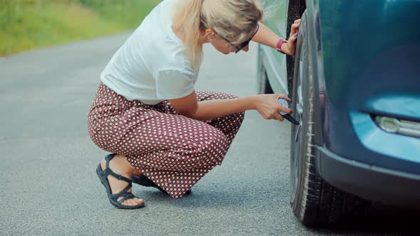 Woman Check Tire Pressure On Car.Car Accident.Broken Vehicle Damage Troubles.Car Deflated Tire.