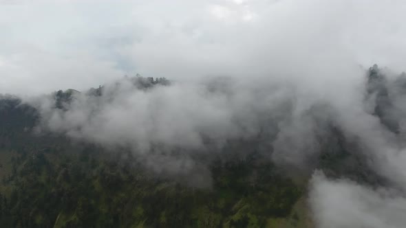 Flying left through clouds in high mountains in Indonesia