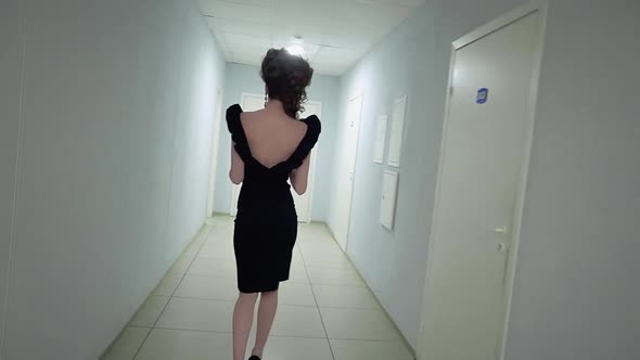 Young Beautiful Girl in the Office in Evening Dress Walking Along the Corridor Slow Motion