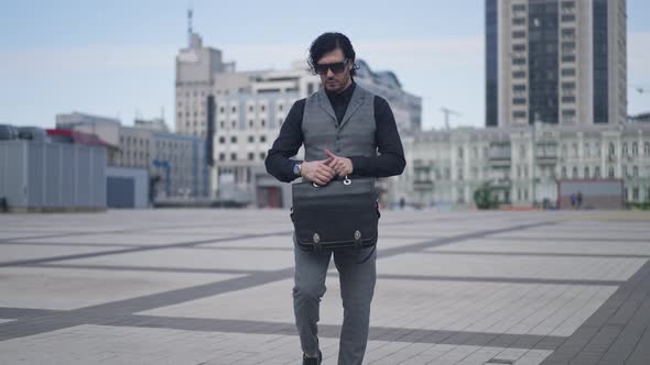 Portrait of Serious Caucasian Successful Businessman Strolling on City Square with Briefcase