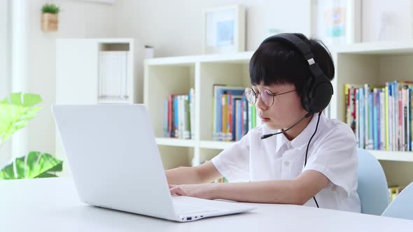 Young student wearing wireless headphones and taking online class on laptop