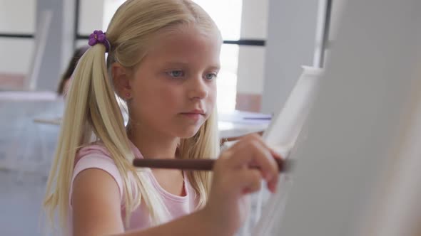 Video of focused caucasian girl painting during art lessons at school