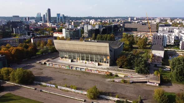 Modern Vilnius downtown and derelict building of Concert and Palace Hall, aerial descend view