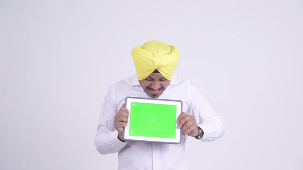 Happy Indian Sikh Businessman Looking Surprised While Showing Digital Tablet