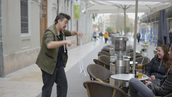 Street Magician Showing Rope Magic Tricks to the Person Sitting on the Cafe Table