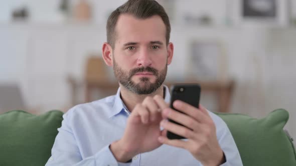 Young Man Using Smartphone at Home