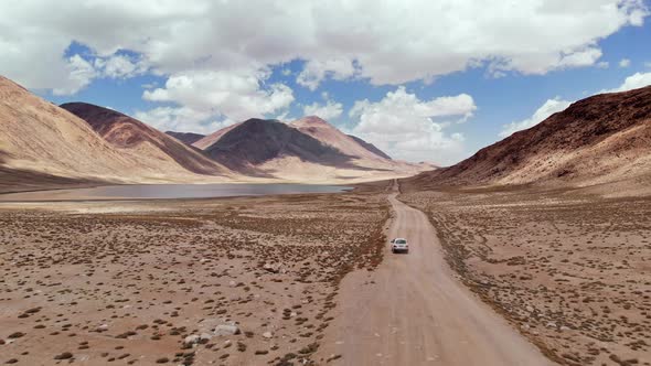 Aerial Over Off Road 4X4 Car Driving Along Gravel Trail Path Near Arid Desert Mountains