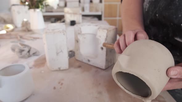 Anonymous artisan shaping ceramic pot with knife