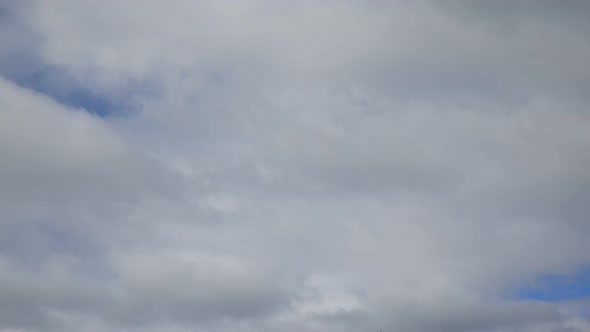 Fast moving white fluffy clouds on a blue sky. Time-lapse of fast approaching cumulus clouds.