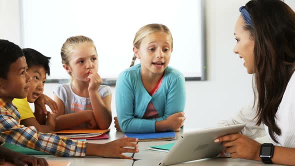 Teacher Teaching School Kids on Digital Tablet in Classroom