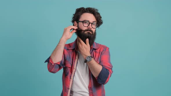 Young Bearded Man Combing His Beard Looking at Camera.