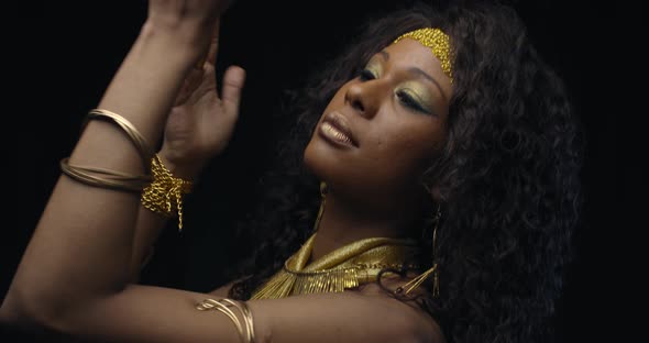 Young Beautiful Woman in Golden Dress with Makeup and Jewelry Is Dancing