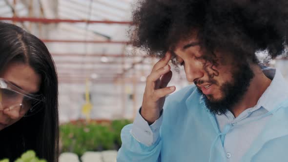 Male and Female Pharmacy Specialists Considers Green Plant in Greenhouse