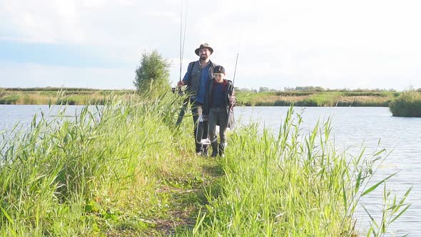 Happy Son Go To Fishing Place, Father Follows, They Hold Fishing Rods