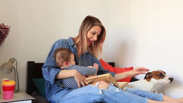 Young mother and son with a dog sitting on a bed. indoor footage