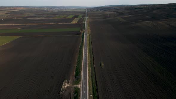 Aerial View of a Road Among Agriculture Fields and Green Countryside
