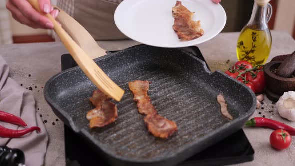 Cooking Pieces of Flavorful Sliced Organic Bacon Fried in Grill Pan