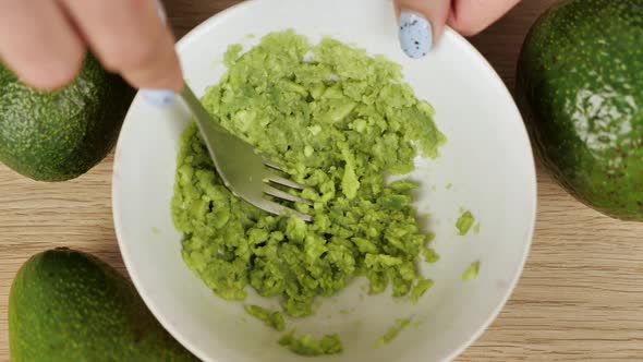 Hands Woman Mashing Avocado in Bowl with a Fork