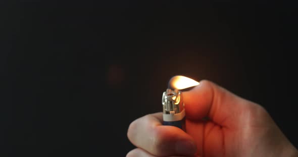 Lighting a lighter with a flame on a dark background