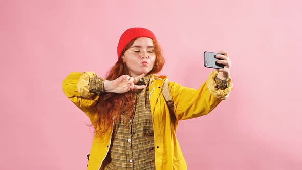 Young Charming Red-haired Girl Takes Pictures of Herself on the Phone.