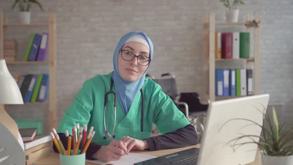 Close Up of Muslim Doctor in Hijab in the Workplace for a Laptop