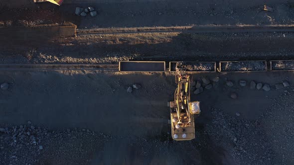 Excavator Loads Ore Into Moving Freight Cars